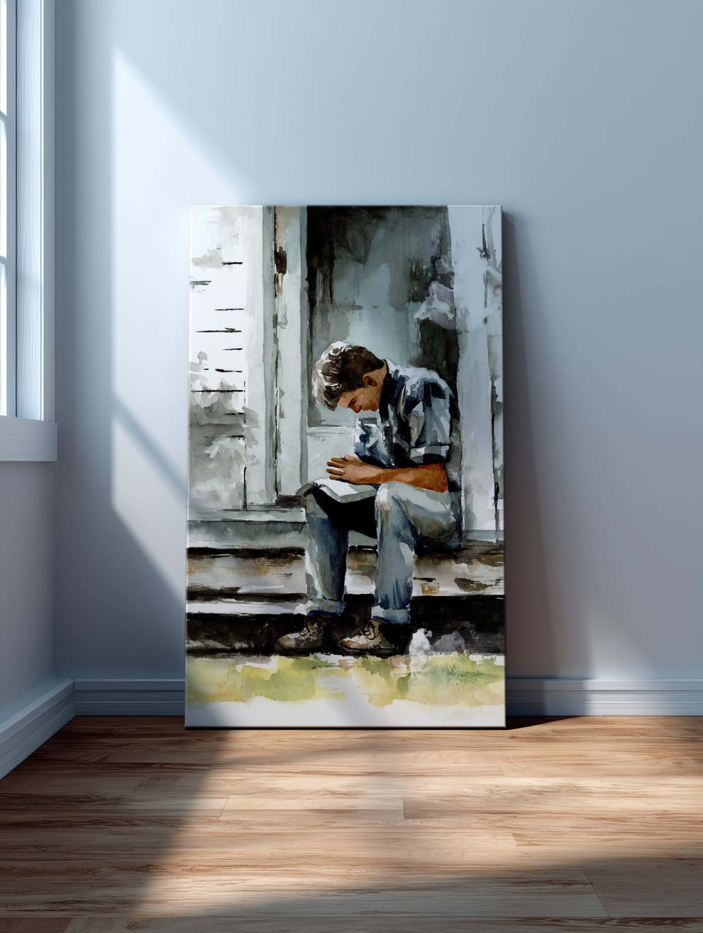 watercolor painting of a young man praying on a porch with scriptures open across his lap painting is large and leaning against a gray wall sitting on a light wood colored floor sitting next to a window the window is casting shadows and light across the p
