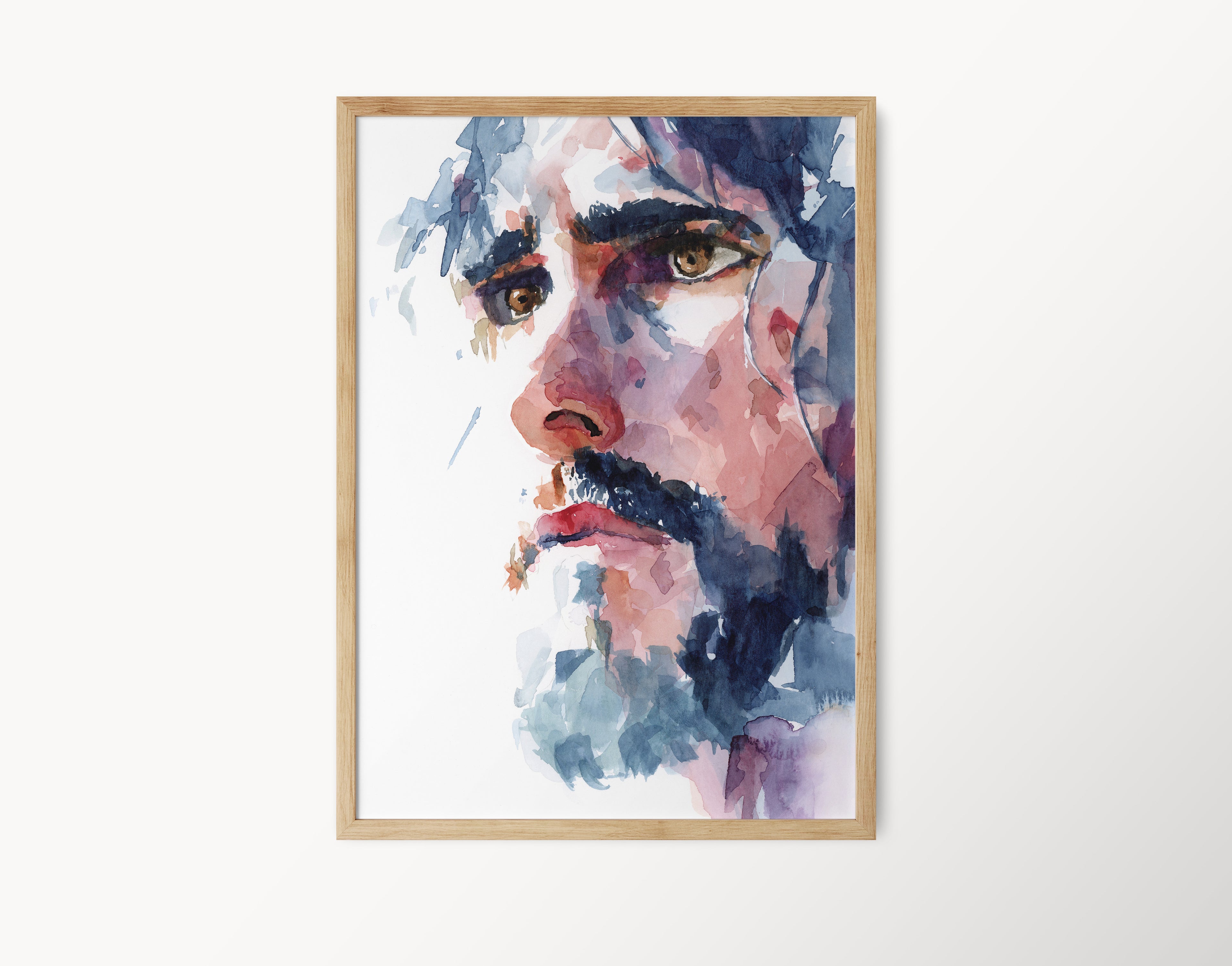Watercolor portrait painting of Christ looking off into the distance with a serious yet gentle expression dark colored hair falls around his face with dark brows and a dark beard and brown eyes painting is in a light wooden colored frame against a white b