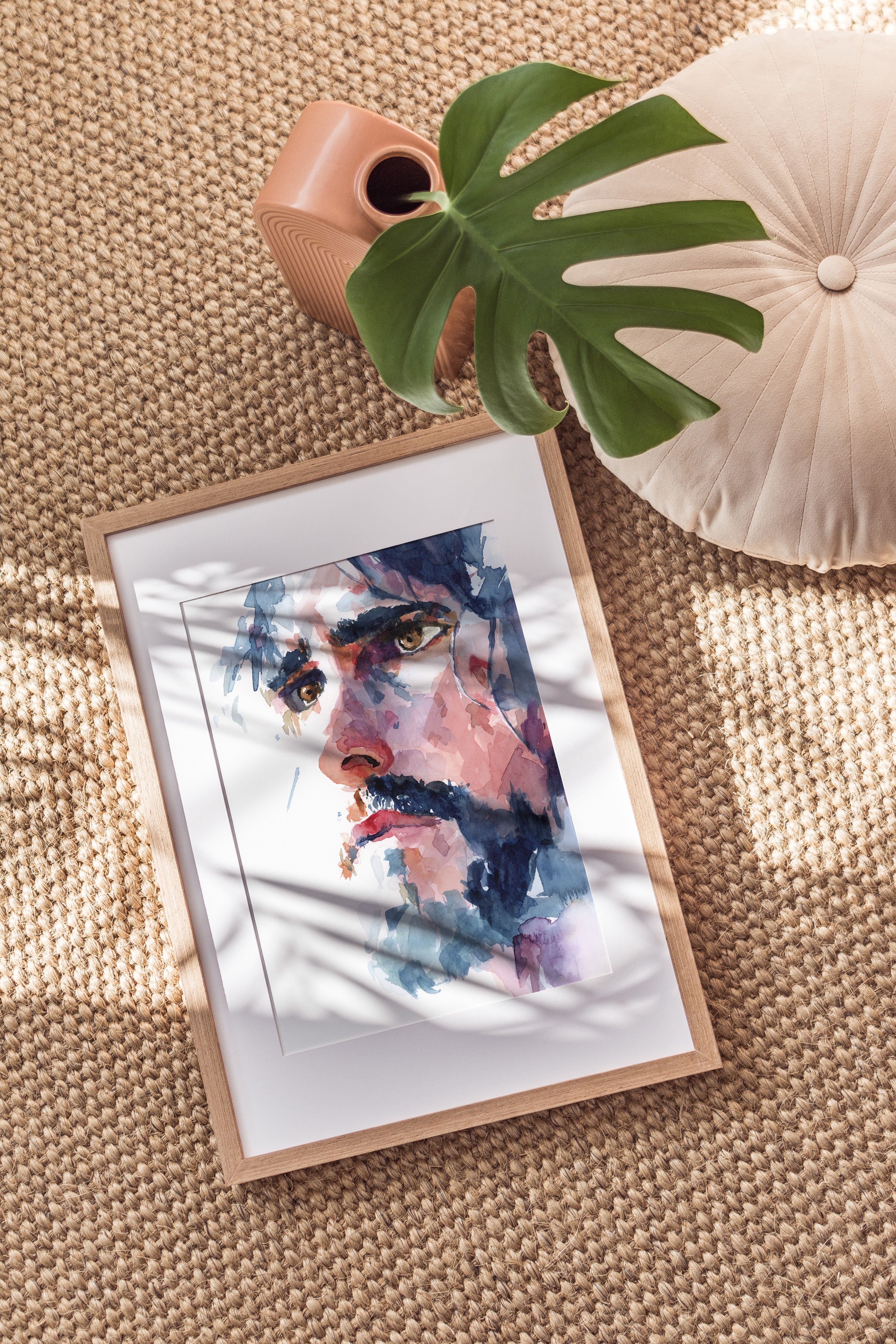 Watercolor portrait painting of Christ looking off into the distance with a serious yet gentle expression dark colored hair falls around his face with dark brows and a dark beard and brown eyes picture is an arial view of the painting in a light colored f