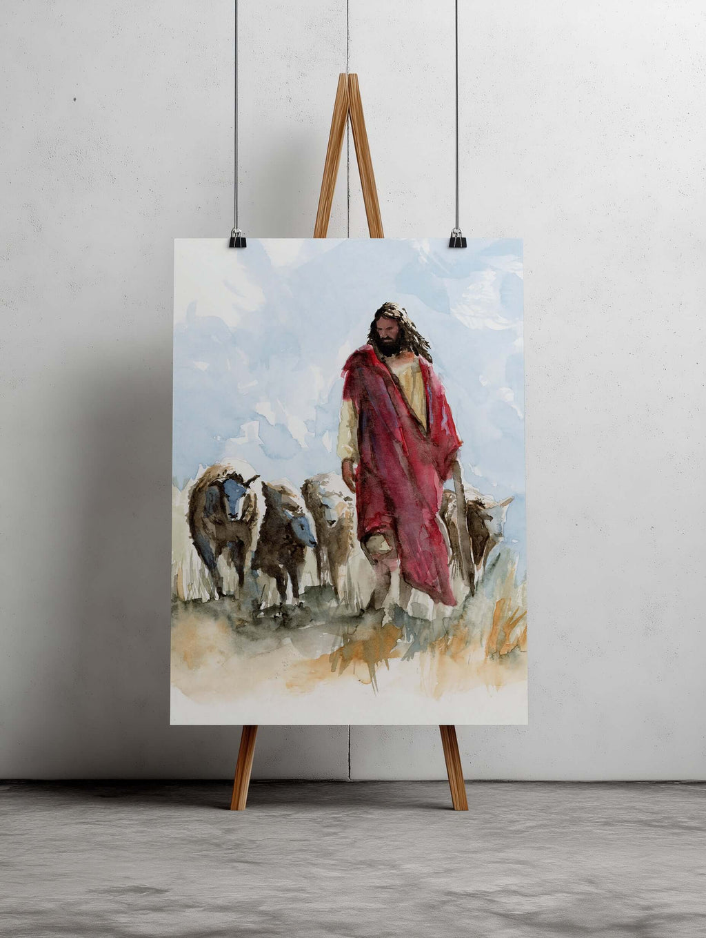 Watercolor painting of Christ dressed in a red robe walking through a field of grasses with 3 sheep there are 3 sheep on his right side and 1 sheep on his left Christ is looking down and there is light blue beautiful skies behind him. Painting is large an